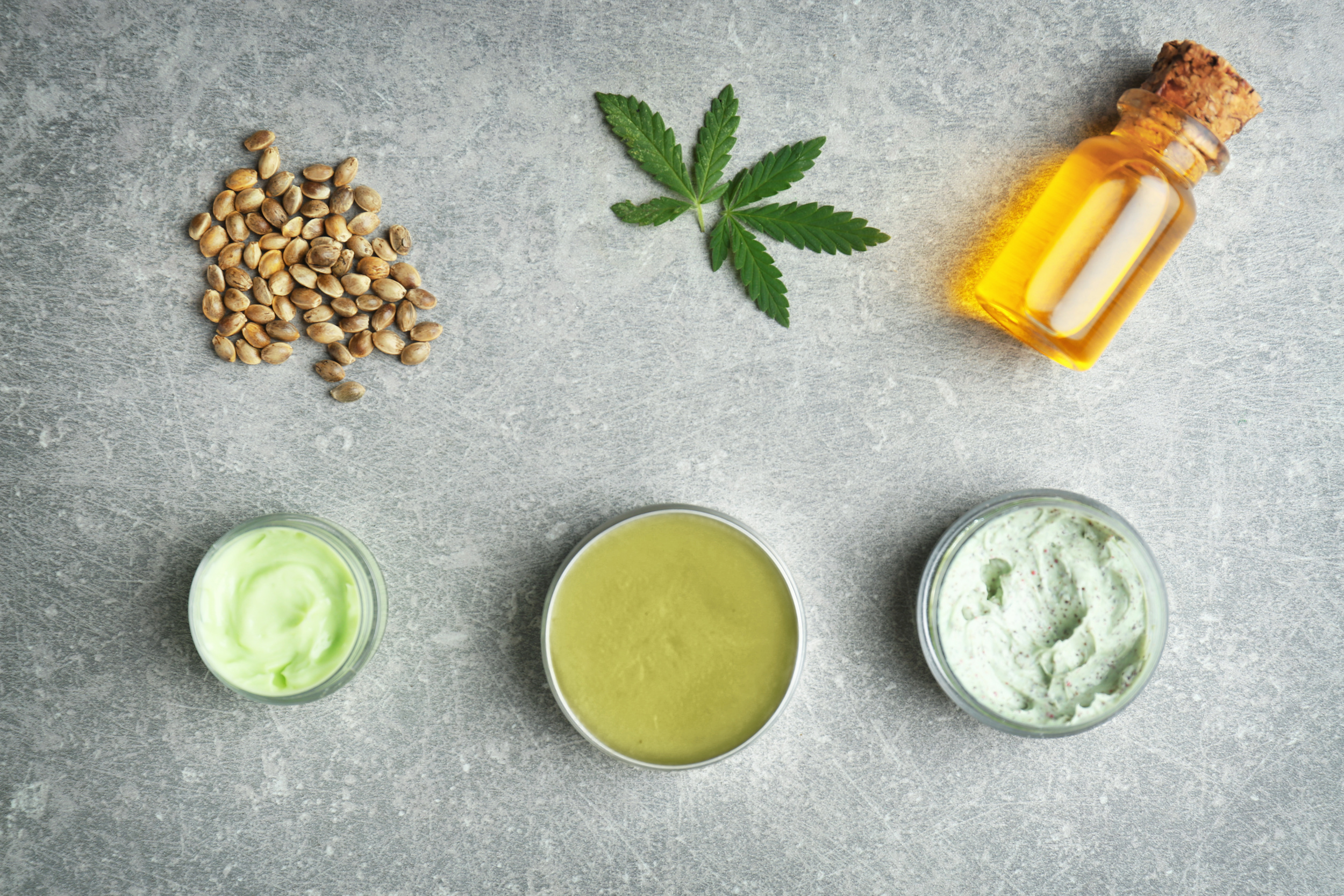 Composition with hemp cosmetic products and natural ingredients on grey background