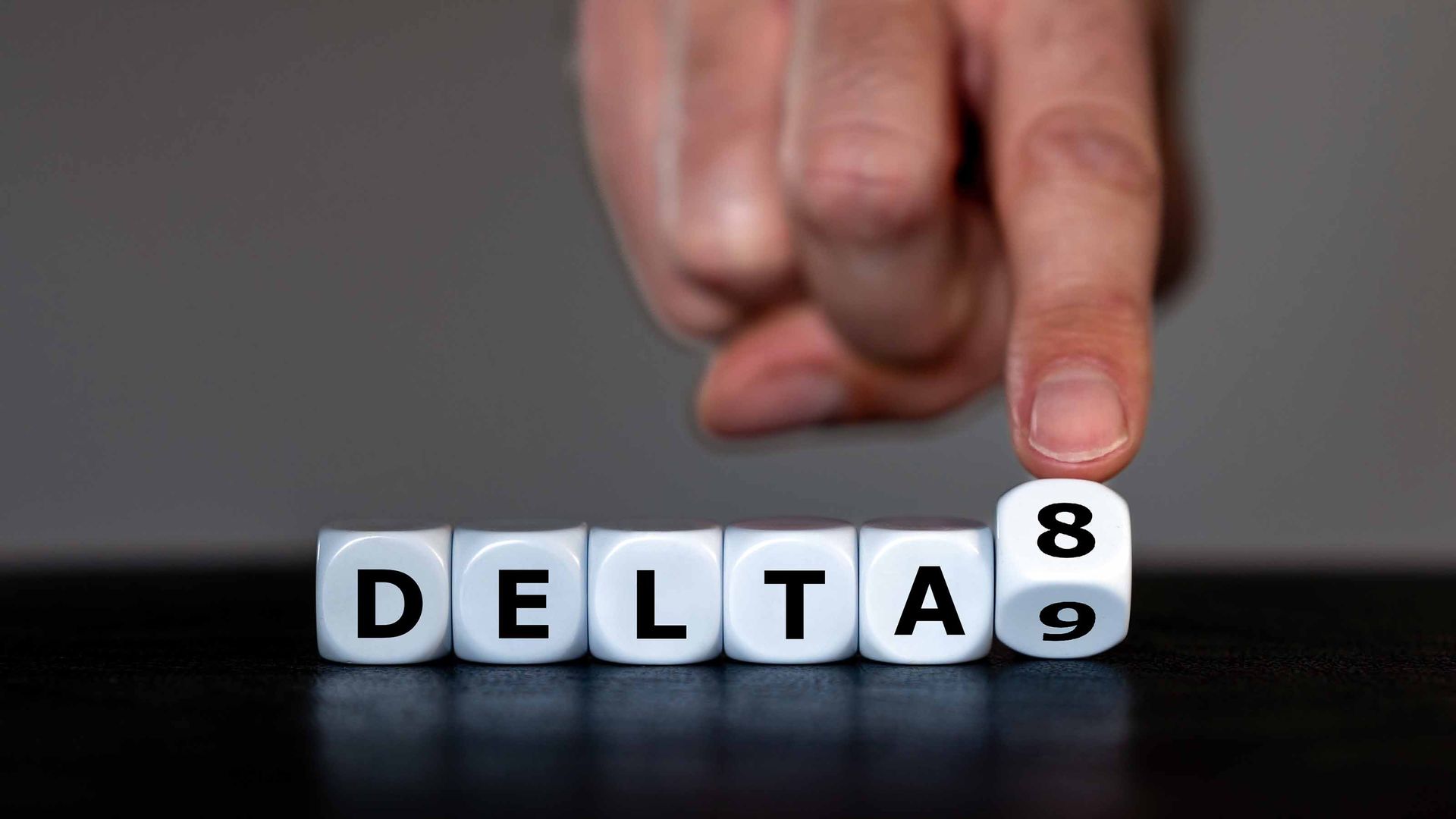 Hand turns dice and changes the expression 'delta 9' to 'delta 8'. Symbol for the Delta-8-tetrahydrocannabinol, a psychoactive cannabinoid found in the Cannabis plant.