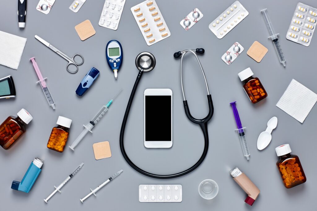 Flat lay of smart phone surrounded with various medical equipmen